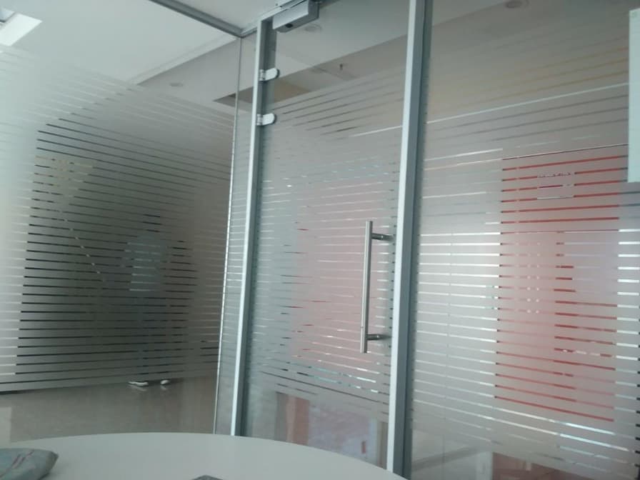 Frosted glass partition with horizontal banding and a door pull.