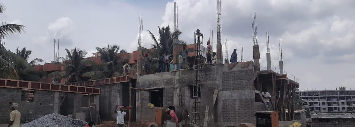 Villas under construction, with block walls below and column reinforcement on the roof.