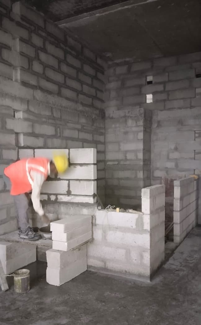 Mason building a block wall at floor level.