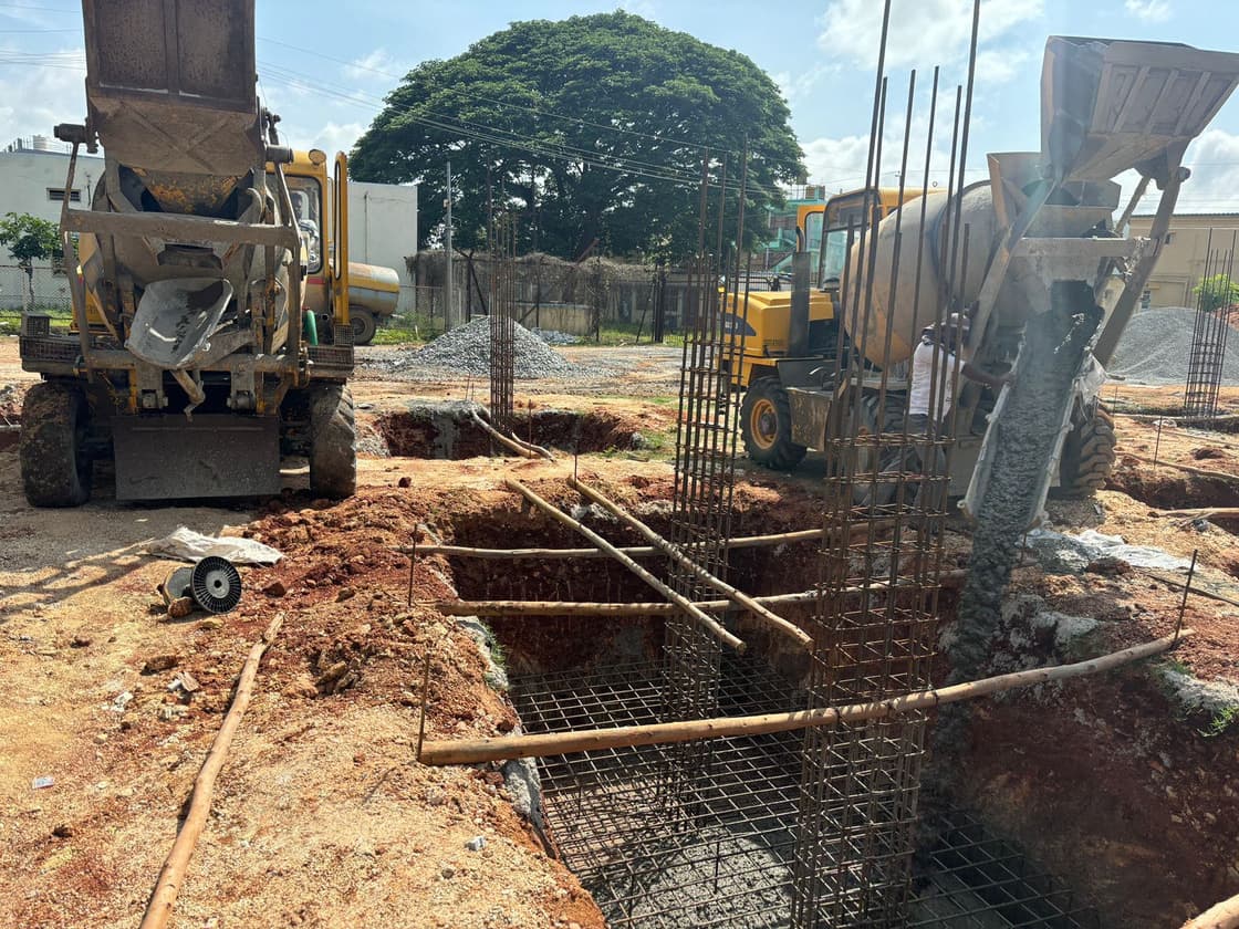 Transit mixer pouring concrete into a footing excavation on a T R Constructions site.