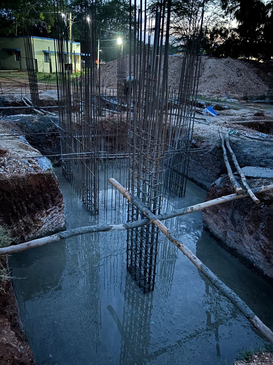 Column reinforcement cages in a footing pit at dusk.