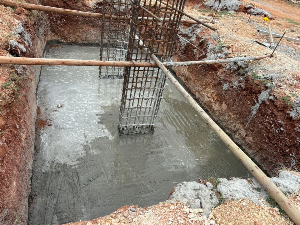 Levelling concrete laid at the base of a footing pit around a column cage.