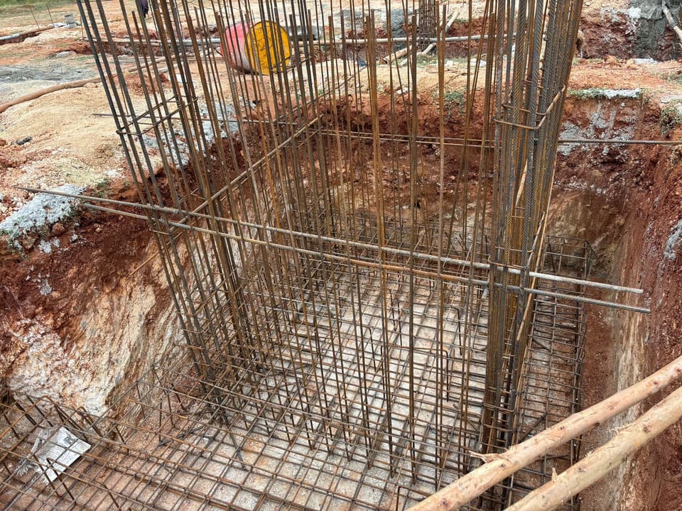 Footing reinforcement mesh and column bars inside an excavated pit.