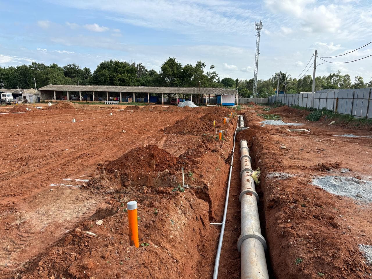 Long trench with a pipeline laid across a plotted layout.