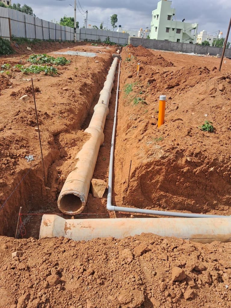 Pipe laid in an open trench alongside a boundary wall.