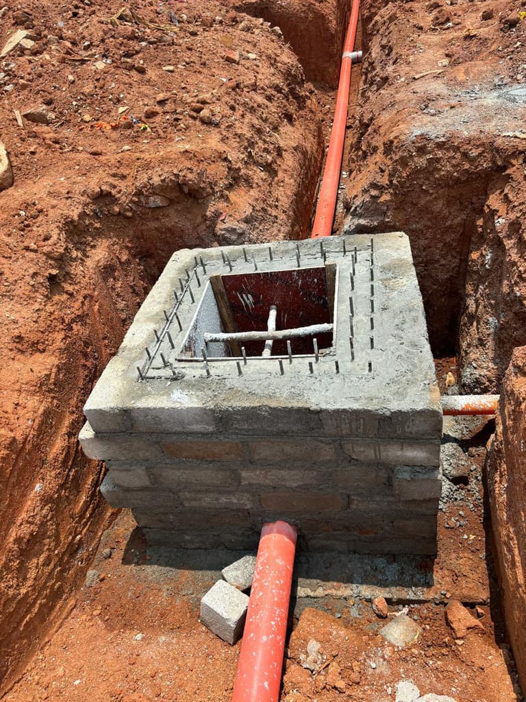 Block-built inspection chamber with pipe connections in a trench.