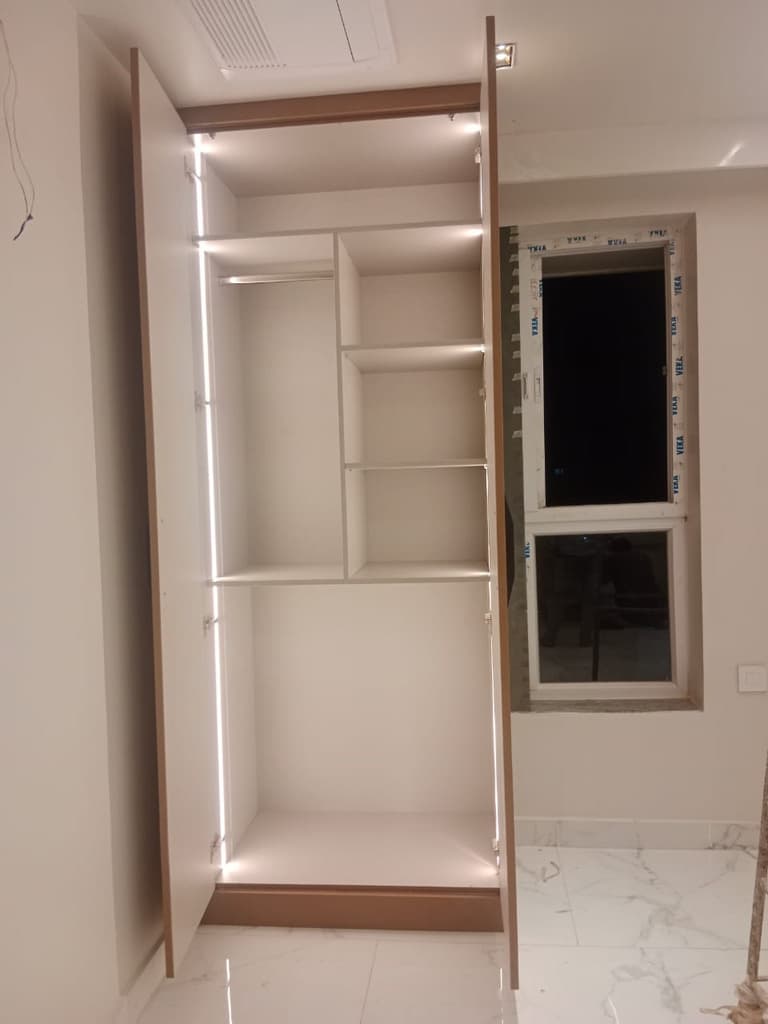 Open storage unit with internal lighting beside a window.