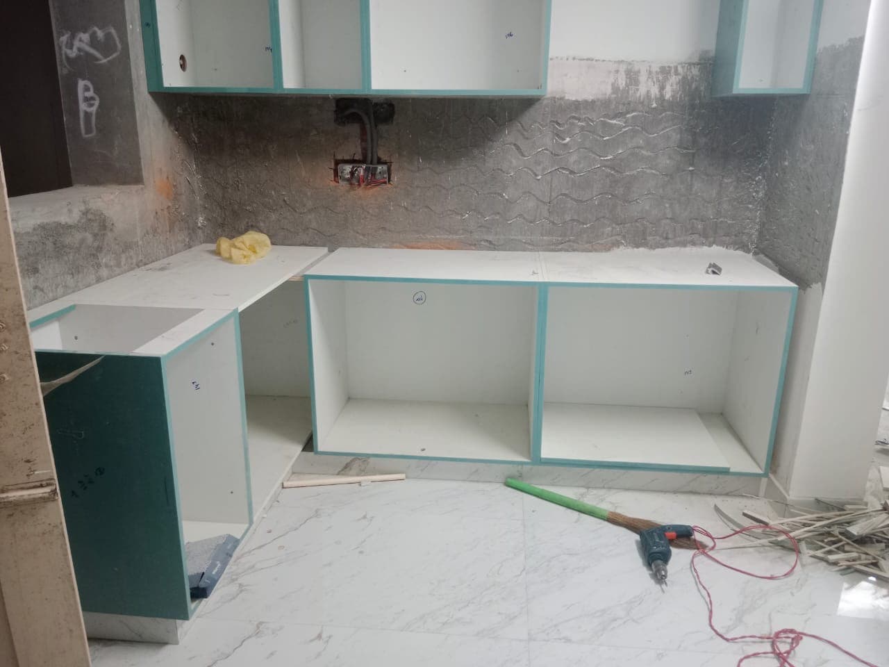 L-shaped kitchen counter with base cabinets being installed.