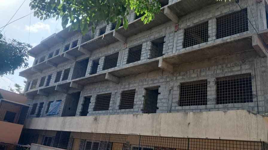 Multi-storey school building with concrete block walls and window openings.