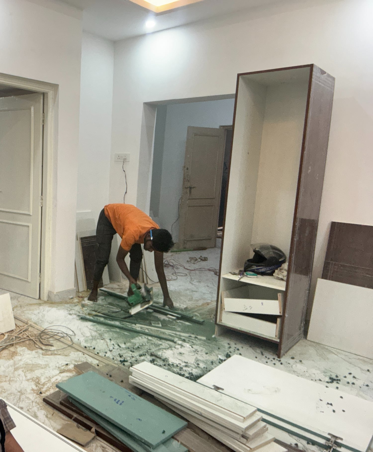 Worker cutting panels for a new storage unit in a home under renovation.